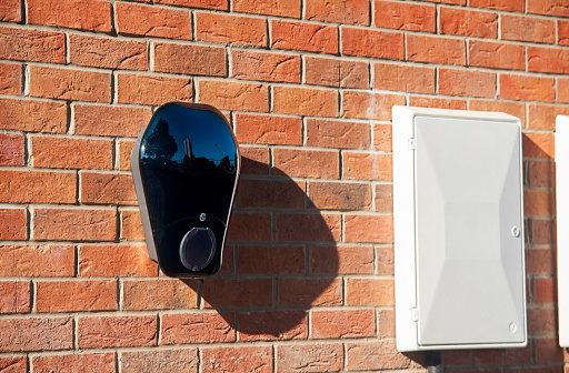 Private electric vehicle charging station fitted to the face of a red brick wall