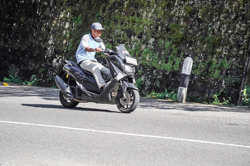 Magetan, Indonesia - August 13, 2023: Motorcycle riders on the highway who do not use or wearing helmets and violate the traffic rules. Concept for safety riding gears, careless, bad bikers.