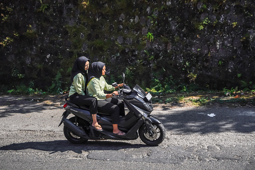 Magetan, Indonesia - August 13, 2023: Motorcycle riders on the highway who do not use or wearing helmets and violate the traffic rules. Concept for safety riding gears, careless, bad bikers.