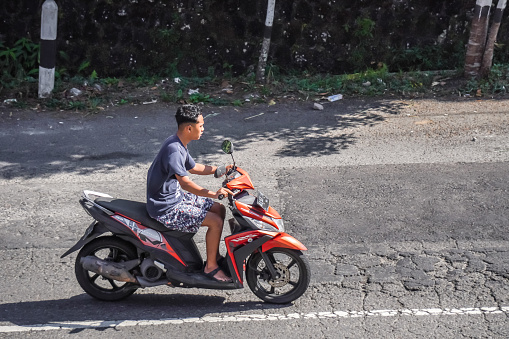 Magetan, Indonesia - August 13, 2023: Motorcycle riders on the highway who do not use or wearing helmets and violate the traffic rules. Concept for safety riding gears, careless, bad bikers.