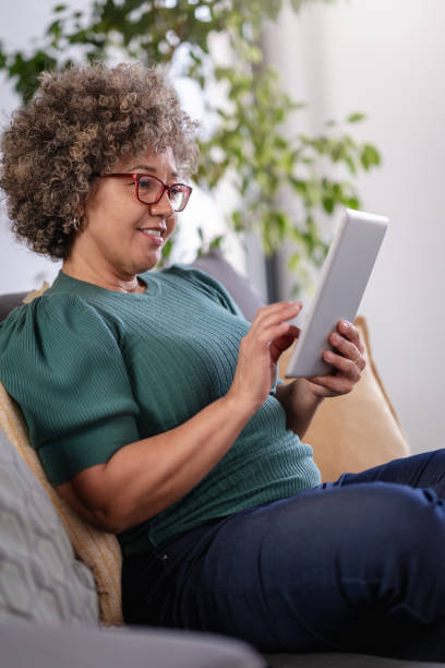 istock Beautiful middle-aged woman using a computer tablet to read a book and surf internet 1917656669