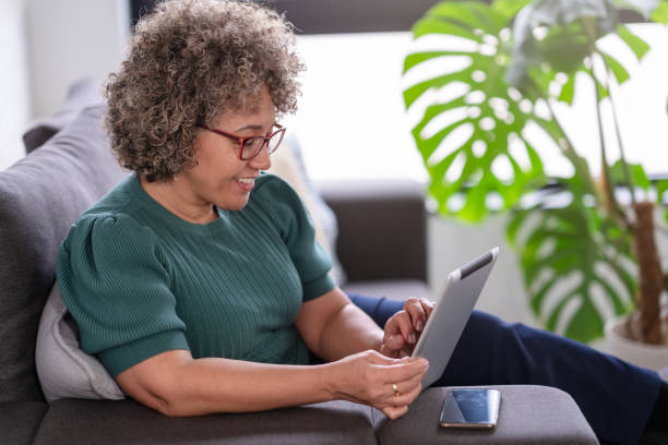 istock Beautiful middle-aged woman using a computer tablet to read a book and surf internet 1917664156