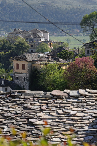 Northeastwards view from the upper part of the old town over several Ottoman-era houses, roofs covered with flat dressed stones, to Arshi Lengo village at Lunxheri mountain foot. Gjirokaster-Albania.