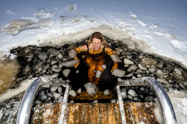 Stockholm, Sweden Stockholm, Sweden A woman ice bathing from a dock into a frozen lake. just do it stock pictures, royalty-free photos & images