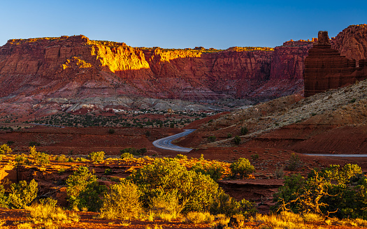 The Chimney Rock formation and red cliffs illuminated by the rising sun in the national park Capitol Reef in Utah early in the morning.