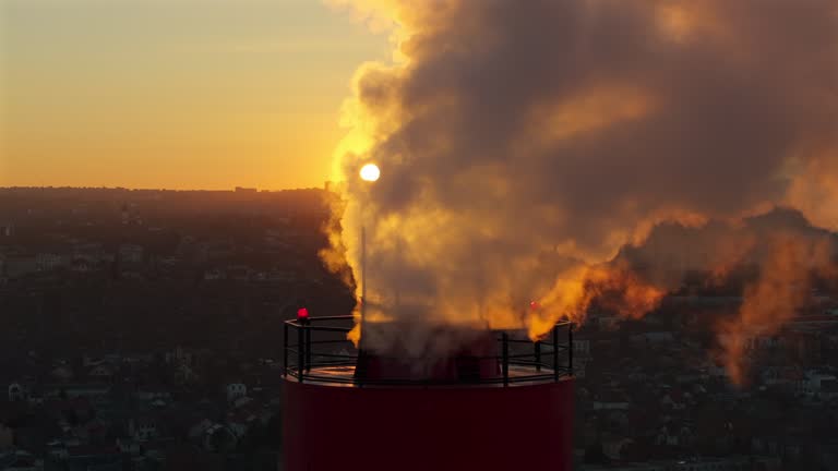 Aerial drone view of thermal power plant at sunset with sun on background. Telephoto medium shot
