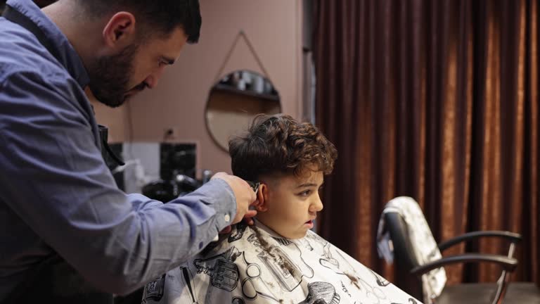 At the barber shop, Caucasian boy getting an hair cut from the young male hairdresser