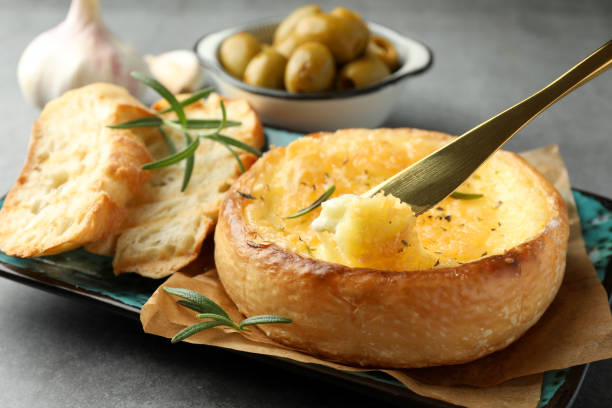 istock Taking tasty baked brie cheese with knife on grey table, closeup 1917813771