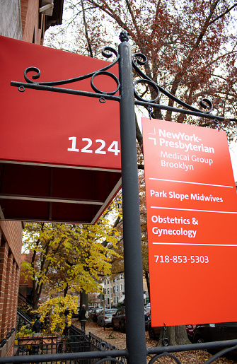 nyc, United States – November 27, 2023: A vibrant orange and yellow sign stands at the entrance of a modern office building in the fall