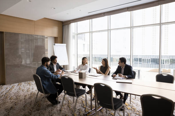 istock Positive multiethnic team of project managers talking at large table 1917815387