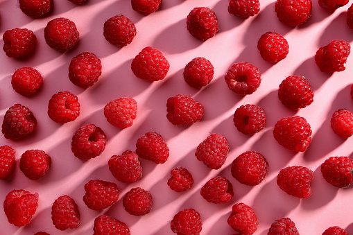 Tasty ripe raspberries on pink background, flat lay