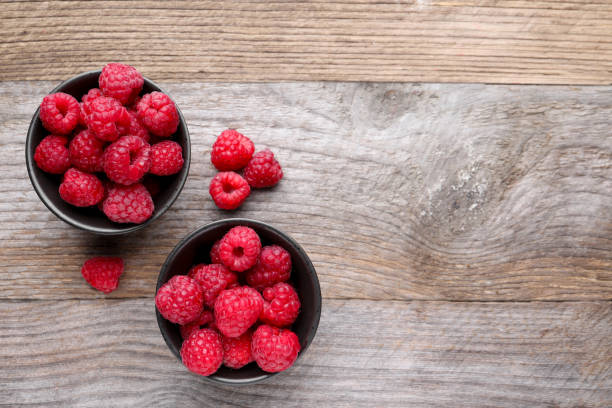istock Tasty ripe raspberries on wooden table, flat lay. Space for text 1917856636