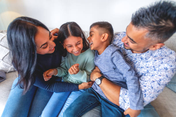 istock Loving  having fun at home playing embracing and cuddling on the sofa. There is a boy and a girl child and 2 parents 1917856647