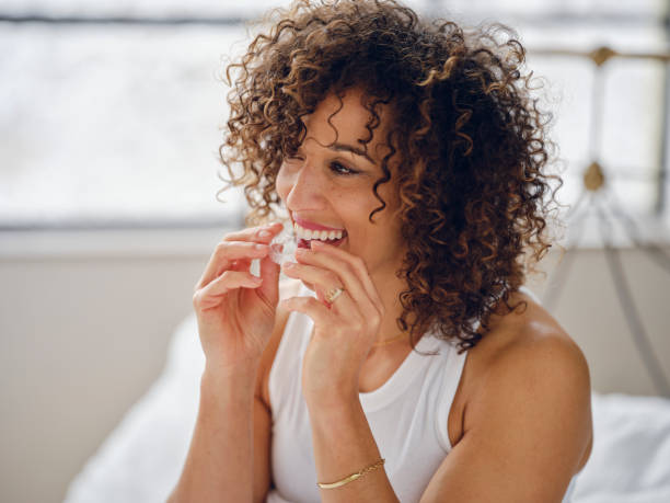istock Woman in Bed in the Morning Using Clear Teeth Aligners 1917858731