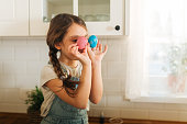Girl having fun while coloring Easter eggs at home in the kitchen