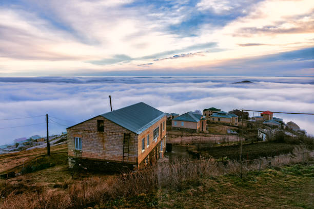 Dagestan, high-mountain village of master jewelers Kubachi. Dawn, the sun is hidden behind the horizon. Two layers of clouds, the top cirrus high in the sky. The lower cumulus clouds are located below the tops of the mountains on which the houses are located.