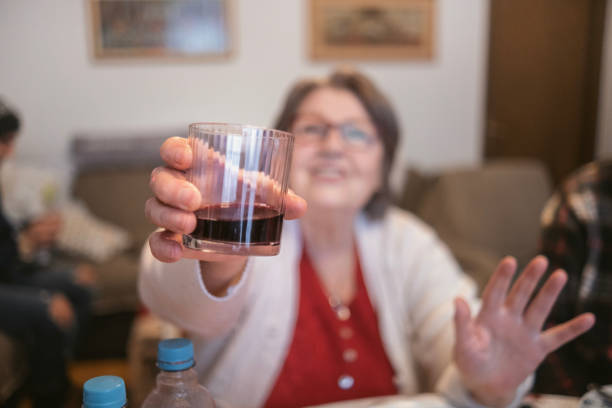Smiling senior woman and her husband toasting with wine on a terrace at sunset.
