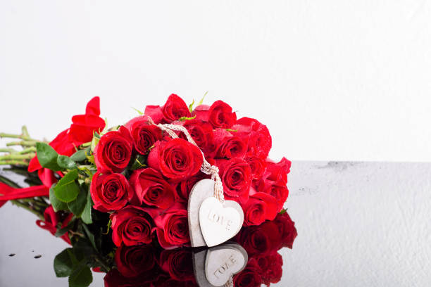букет красных роз сортовой голландской - красная лента с деревянными сердечками на ленте лежат на зеркальной черной поверхности на белом ф� - wedding reception valentines day gift heart shape стоковые фото и изображения