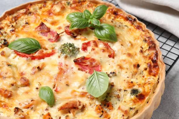istock Tasty quiche with tomatoes, basil and cheese on light textured table, closeup 1917914134