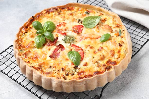 istock Tasty quiche with tomatoes, basil and cheese on light textured table, closeup 1917914405