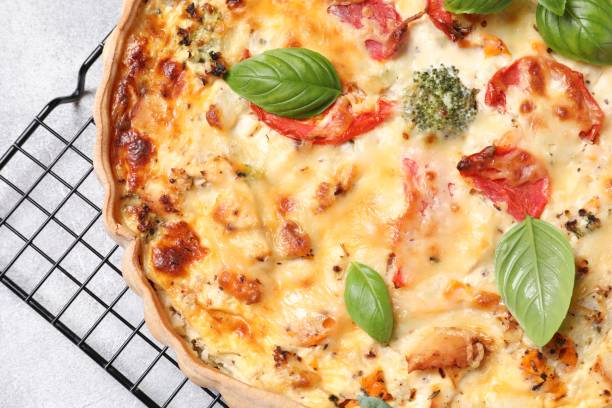 istock Tasty quiche with tomatoes, basil and cheese on light textured table, top view 1917914424