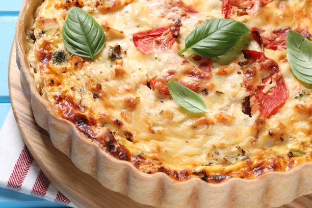istock Tasty quiche with tomatoes, basil and cheese on light blue table, closeup 1917914956