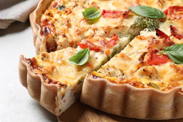 istock Tasty quiche with tomatoes, basil and cheese on light textured table, closeup 1917914963