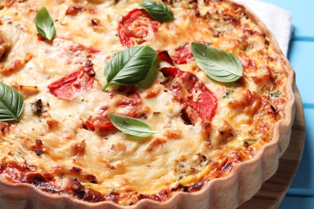 istock Tasty quiche with tomatoes, basil and cheese on light blue table, closeup 1917920197