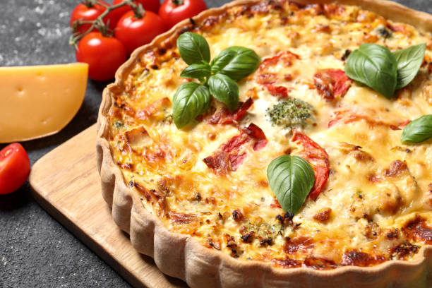 istock Tasty quiche with tomatoes, basil and cheese served on dark textured table, closeup 1917921245