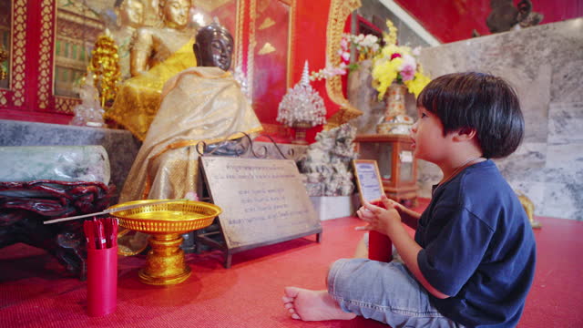 A little boy using a fortune telling tool at the temple.