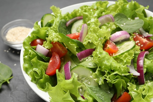 Delicious salad in bowl on grey table, closeup