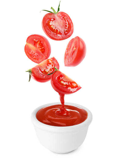 istock Cut tomatoes falling into bowl with organic ketchup on white background 1917960205