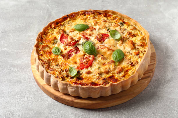 istock Tasty quiche with tomatoes, basil and cheese on light table 1917963416