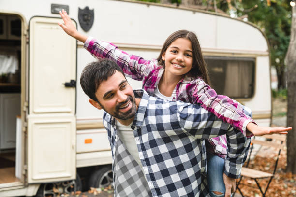 preteen glückliche tochter kind macht huckepack mit jungem vater auf einer roadtrip-reise urlaub mit wohnmobil rad wohnmobilanhänger zusammen. froher vatertag! - motor home mobile home isolated vehicle trailer stock-fotos und bilder