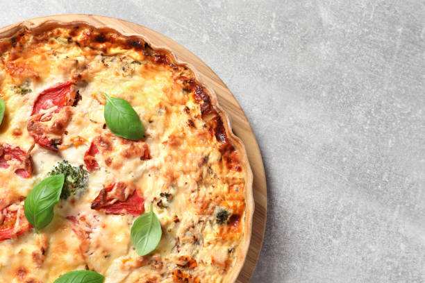 istock Tasty quiche with tomatoes, basil and cheese on light table, top view. Space for text 1917966561