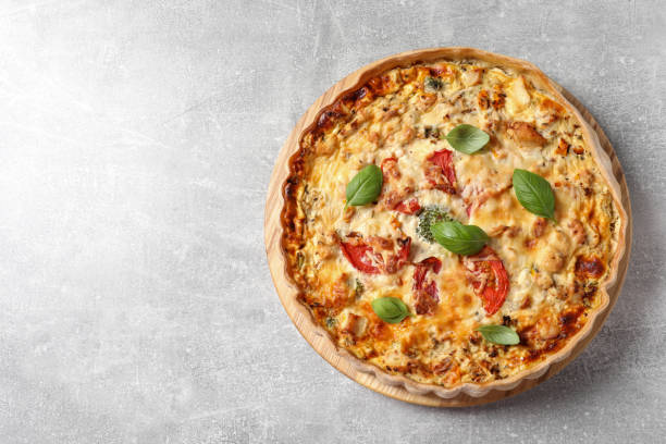 istock Tasty quiche with tomatoes, basil and cheese on light table, top view. Space for text 1917966570