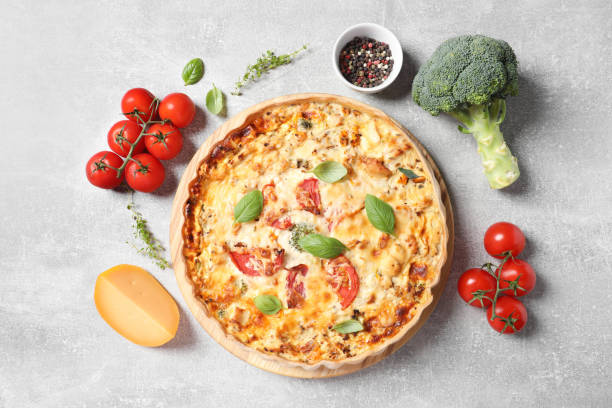 istock Flat lay composition of tasty quiche with tomatoes, basil and cheese served on light table 1917967077