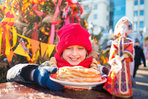 smiling boy is going to eat pancakes  at the traditional Russian festival dedicated to the meeting of spring, the week of pancakes, Shrovetide. decorations for the Maslenitsa holiday