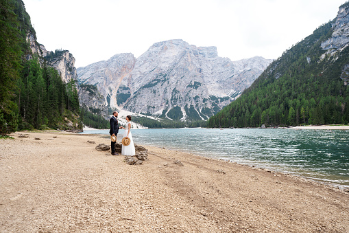 Just got married couple at lake braies in italy standing at the inconic dolomite mountains and amazing lake braies.