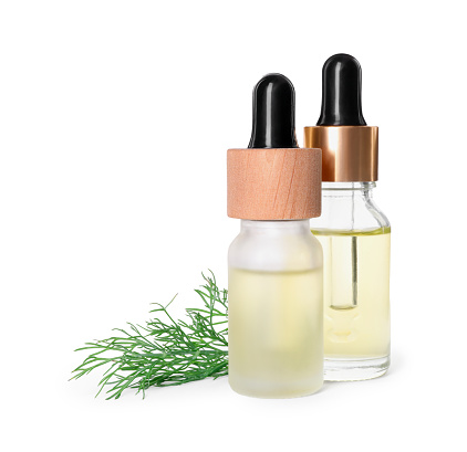 Bottles of essential oil and fresh dill isolated on white