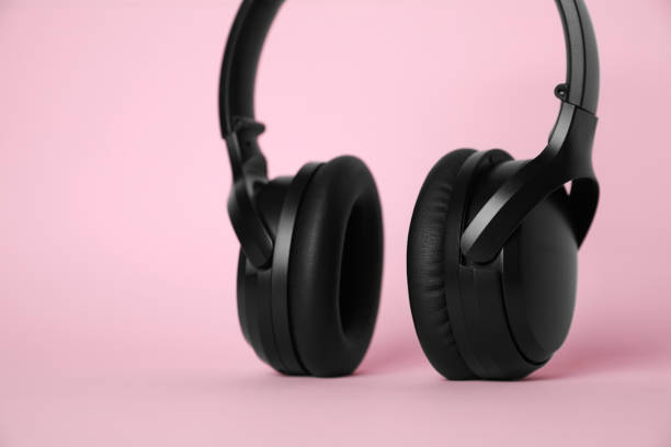 istock Modern wireless headphones on pink background, closeup 1918026086