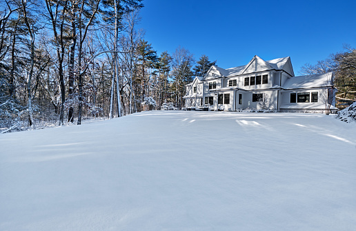 Lake House in winter time. Large home in wooded area on the water edge of the lake. Georgian Bay area of Ontario province, Canada.
