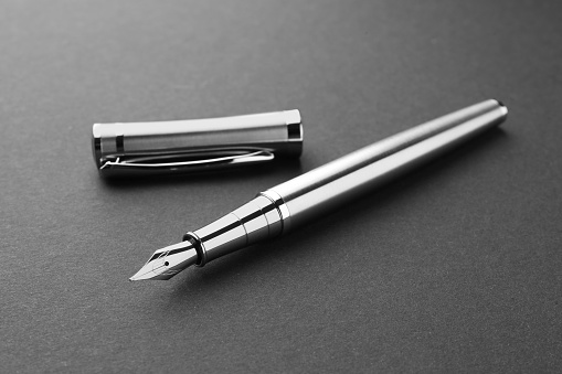 Stylish silver fountain pen with cap on dark background, closeup