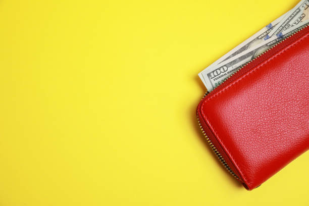 istock Stylish red leather purse with dollar banknotes on yellow background, top view. Space for text 1918036555