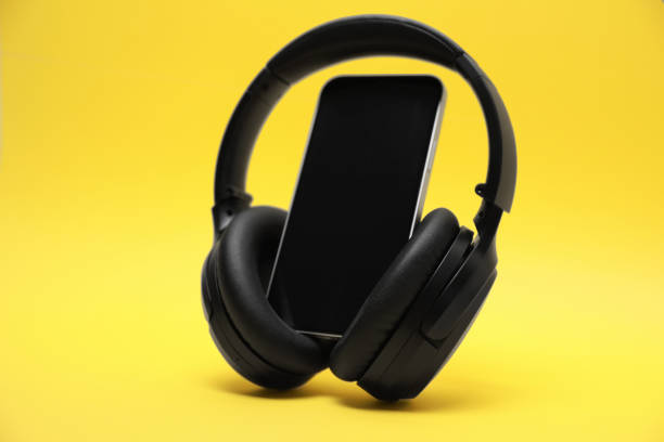 istock Modern wireless headphones and smartphone on yellow background 1918038657