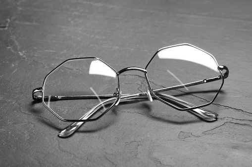 Glasses in stylish frame on black table, closeup