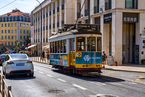 Lisbon, Portugal - May 22, 2022: Well-known tram in Lisbon Portugal with tourists and graffiti on summer day.