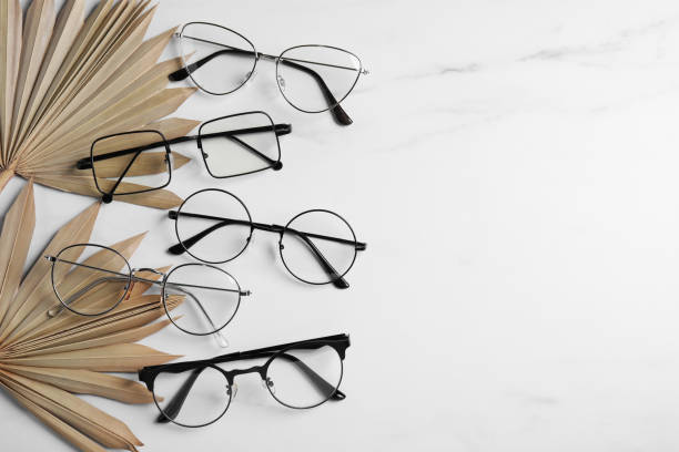 istock Many glasses in stylish frames and leaves on white marble table, flat lay. Space for text 1918055639