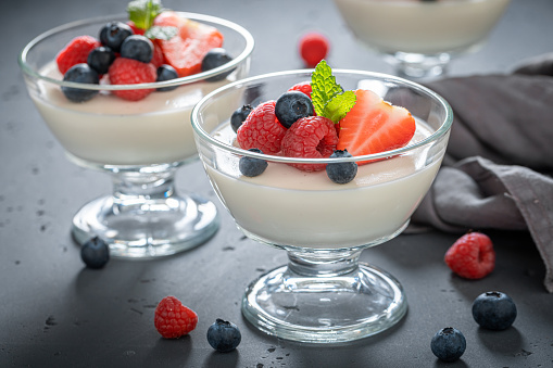 Homemade no-bake banana pudding in individual servings of a Southern USA classic dessert made with bananas, vanilla pudding, vanilla wafers and topped with meringue, with a bunch of bananas in background