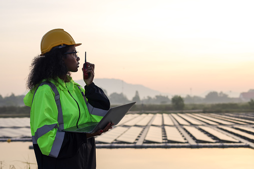 International Women's Day, Female worker using walkie-talkie work on-site of the floating solar farm